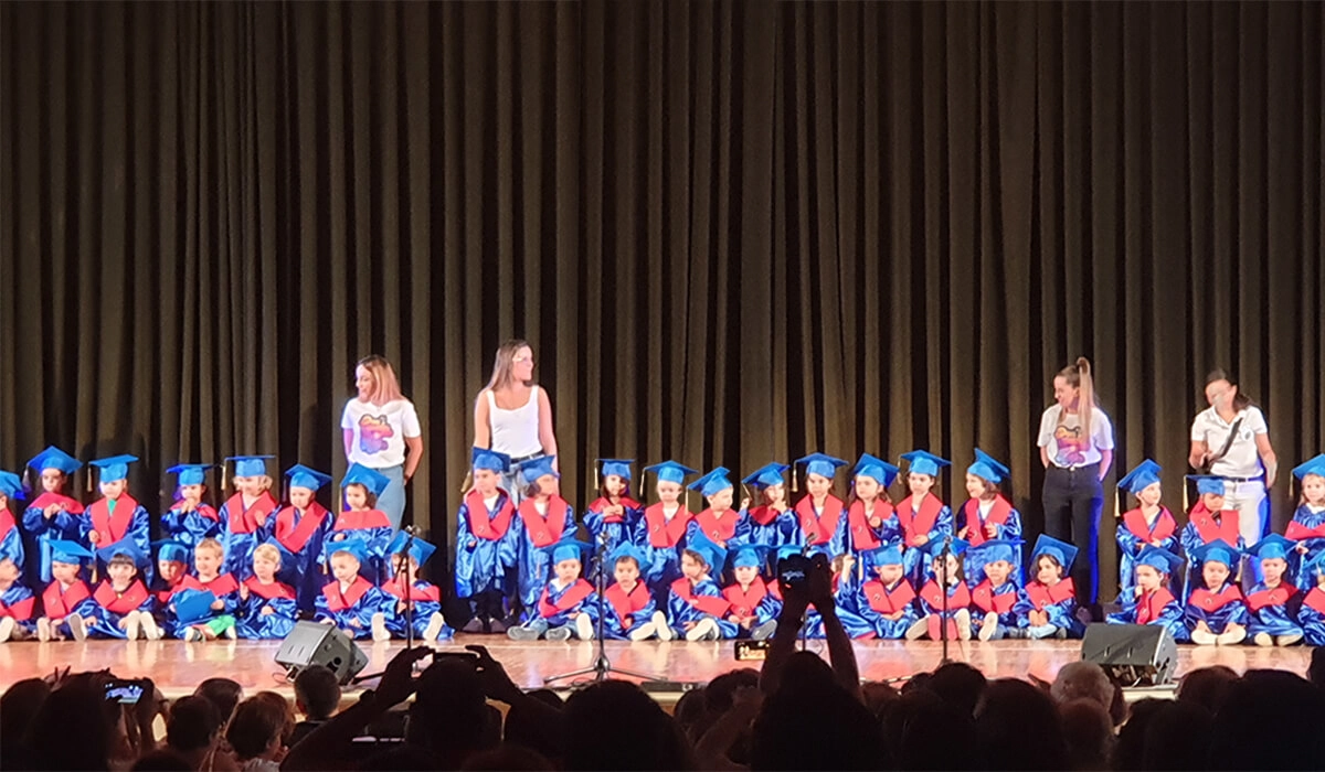 alumnos escuela infantil en acto de graduacion con toga birrete beca