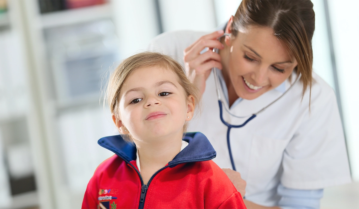 niña pequeña de una escuela infantil siendo auscultada por médica