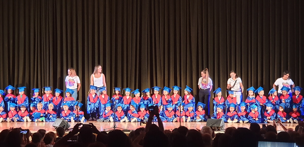 alumnos escuela infantil en acto de graduacion con toga birrete beca