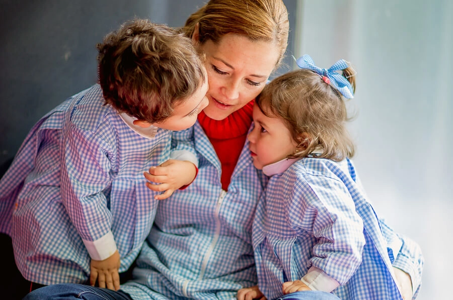 educadora infantil abrazando a dos alumnos pequeños